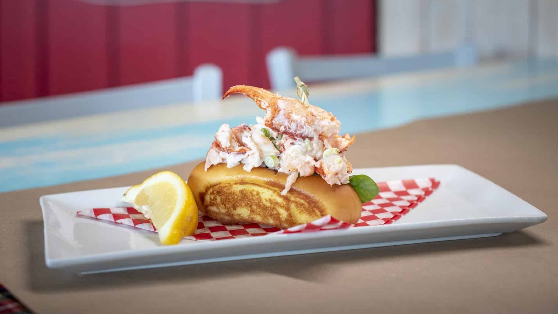 A lobster roll in a toasted bun sits on a white rectangular plate.