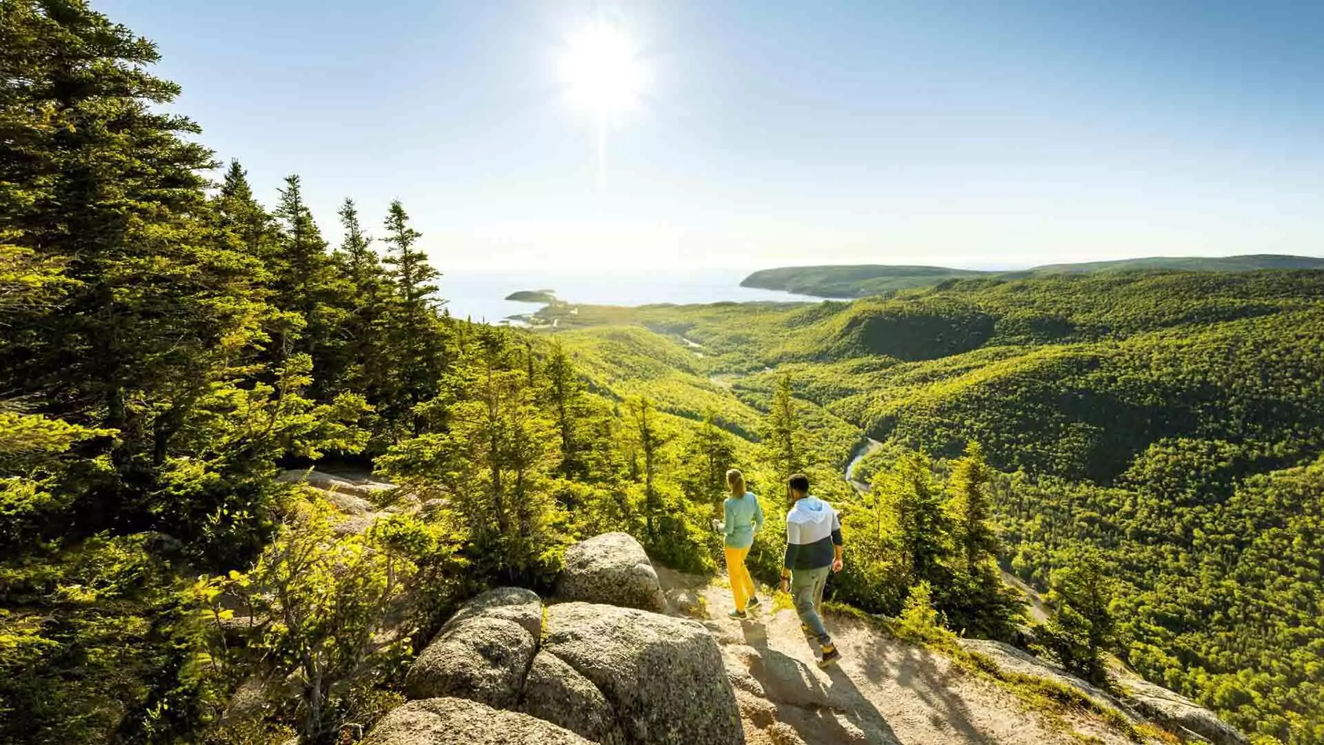 Two hikers walking along the Franey Trail, surrounded by scenic views and lush greenery.