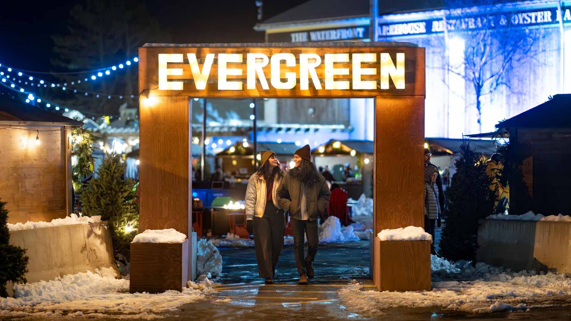 Two people walk through the main entrance of the Evergreen Festival on the Halifax Waterfront in Halifax Nova Scotia on a wintery evening