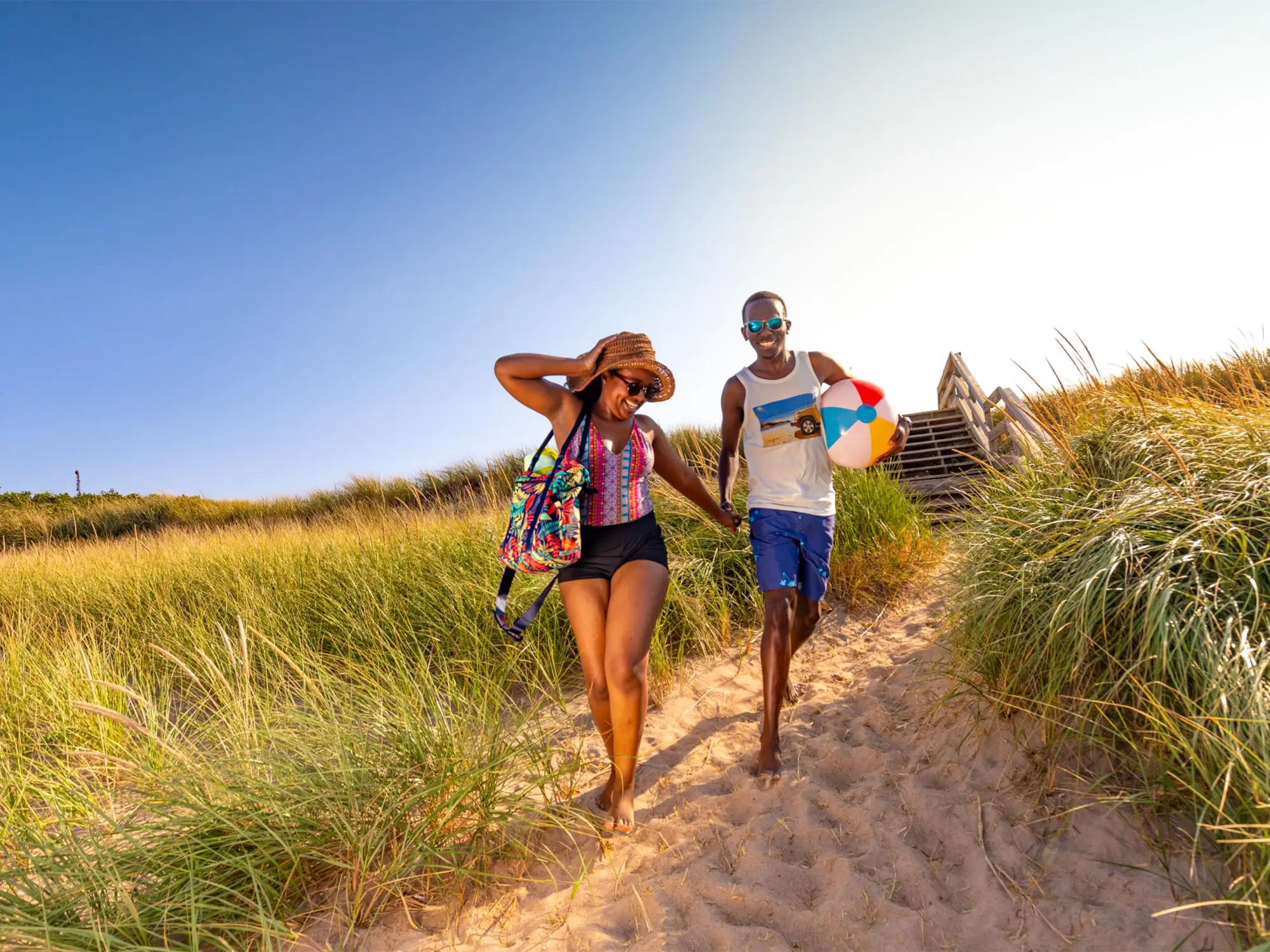 A couple running on the sand dunes at Melmerby Beach